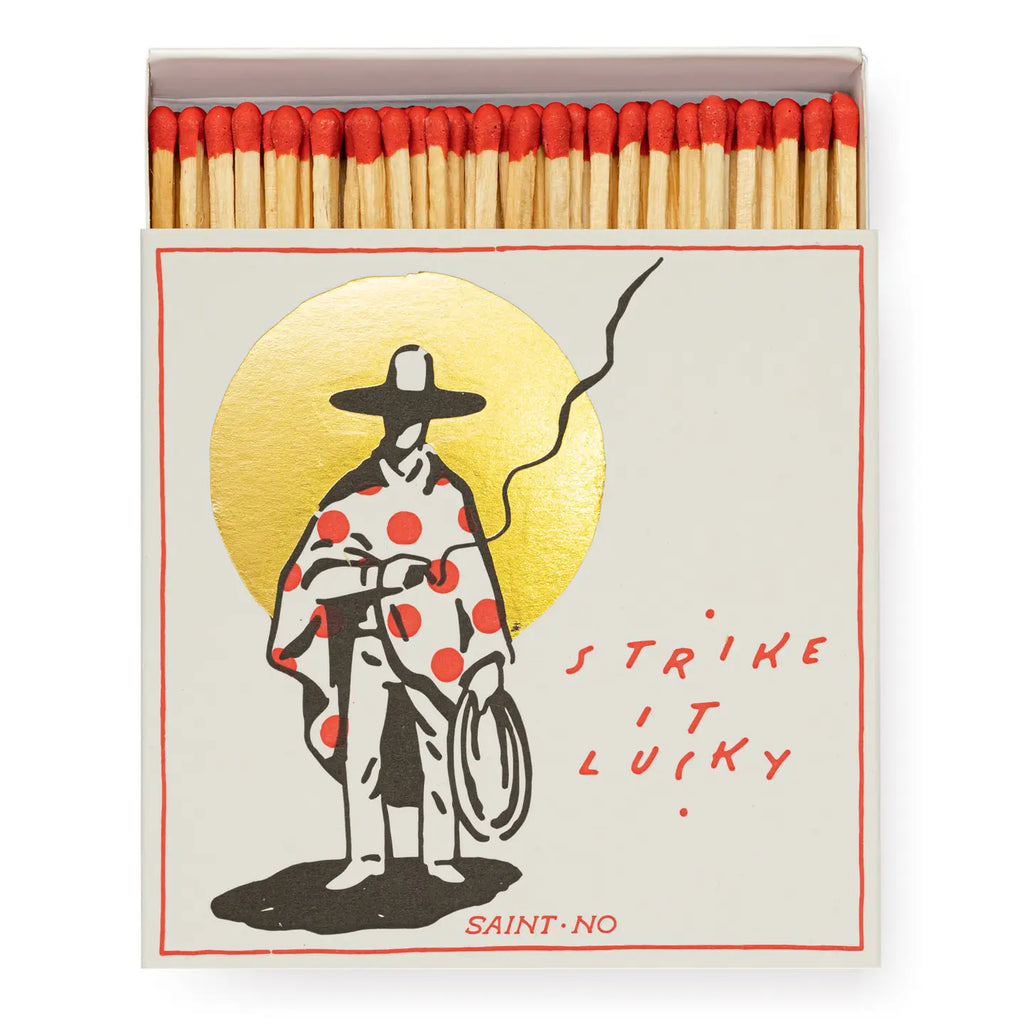 Matches with a design of a person in a polka dot coat and hat, holding a cane, with text 'Strike it lucky' on a white background.